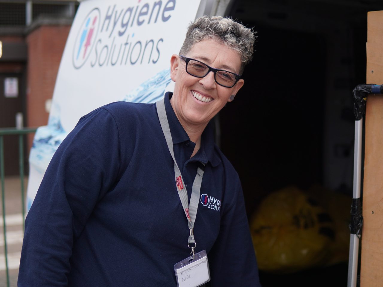 Smiling Hygiene Solutions service engineer beside a branded van