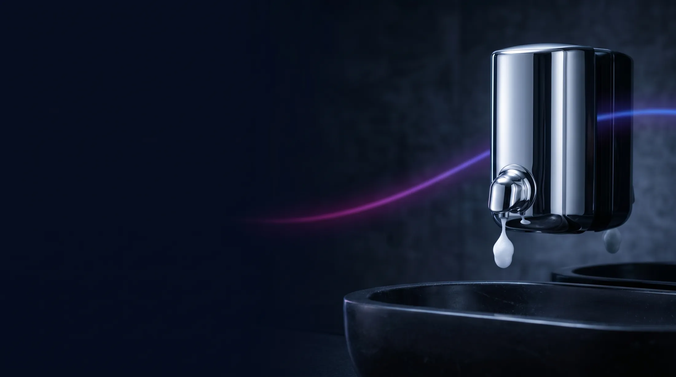 A chrome soap dispenser above a basin in a premium commercial washroom